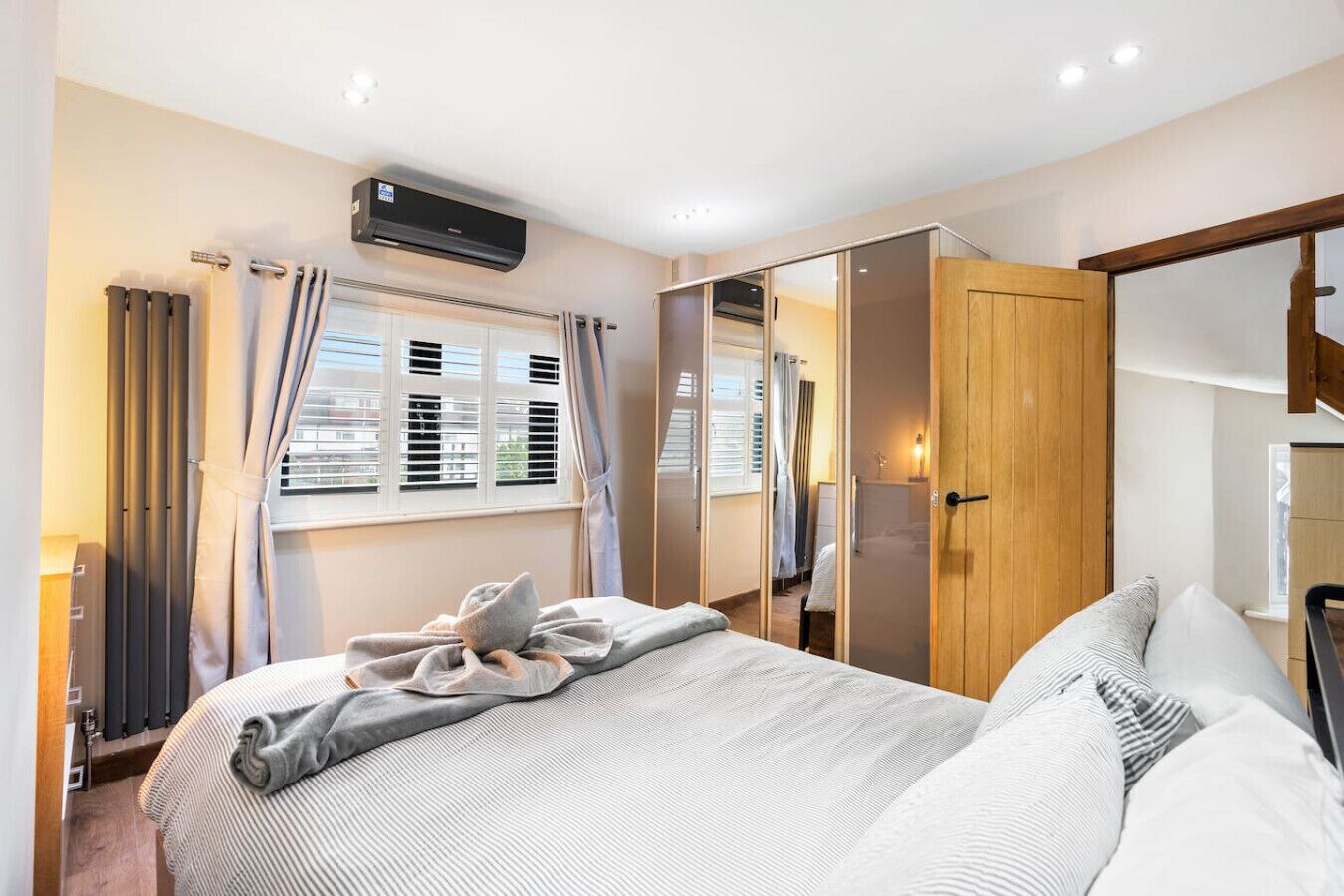 Une chambre à coucher comprenant un lit, une armoire, un radiateur et une fenêtre avec des stores.
