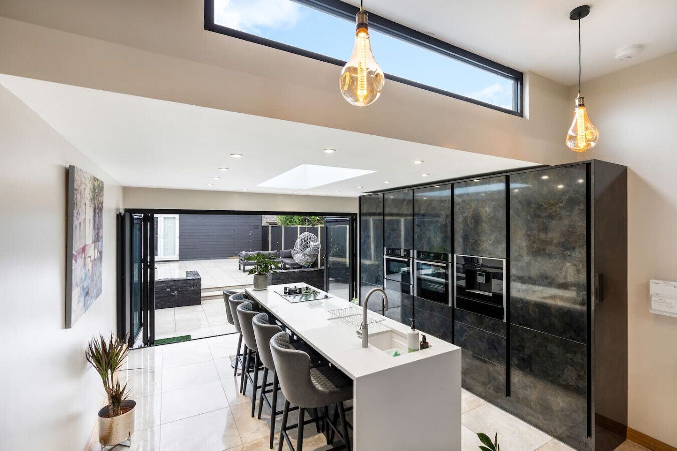 A modern kitchen with a central island, black cabinetry, and pendant lighting.