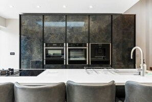 Une cuisine moderne dotée d’un îlot central, de fours encastrés et d’un robinet élégant.
