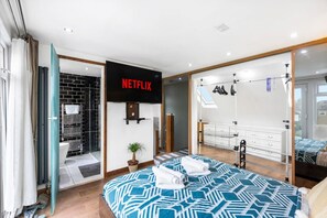 A modern bedroom with a large bed, a wardrobe, a hanging shoe rack, and a sign for Netflix. - Modern 5 Bedroom House in Hove, Sleeps 8, Van & Car Parking, EV Plug (Brighton and Hove)
