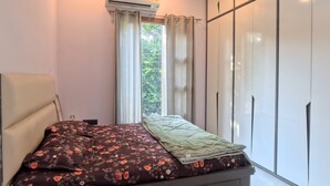 A modern bedroom with a bed, a ceiling fan, an air conditioning unit, and a wardrobe. - Charming B&B Retreat in the Heart of Cha (Chandigarh)