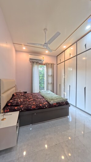 A modern bedroom with a bed, a ceiling fan, an air conditioning unit, and a wardrobe. - Charming B&B Retreat in the Heart of Cha (Chandigarh)