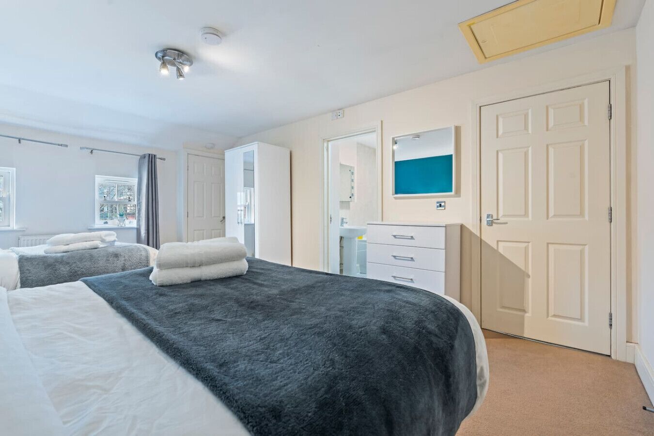 A hotel room with two beds, a bathroom, and a view of the outside.