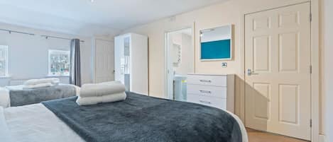 A hotel room with two beds, a bathroom, and a view of the outside.