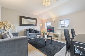 Ein modernes Wohnzimmer mit einem grauen Sofa, einem Couchtisch und einem Fernseher mit dem Netflix-Logo.
