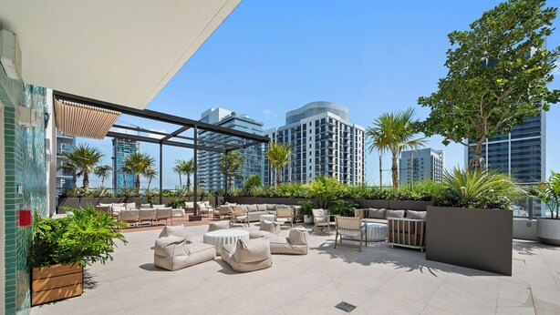 An outdoor patio area with seating arrangements, a pool, and a view of surrounding buildings. - The Crosby Balcony Studio Palermo Home (Miami)