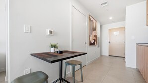 A modern interior with a dining table, two chairs, a potted plant, and a large abstract painting on the wall. - The Crosby Balcony Studio Palermo Home (Miami)