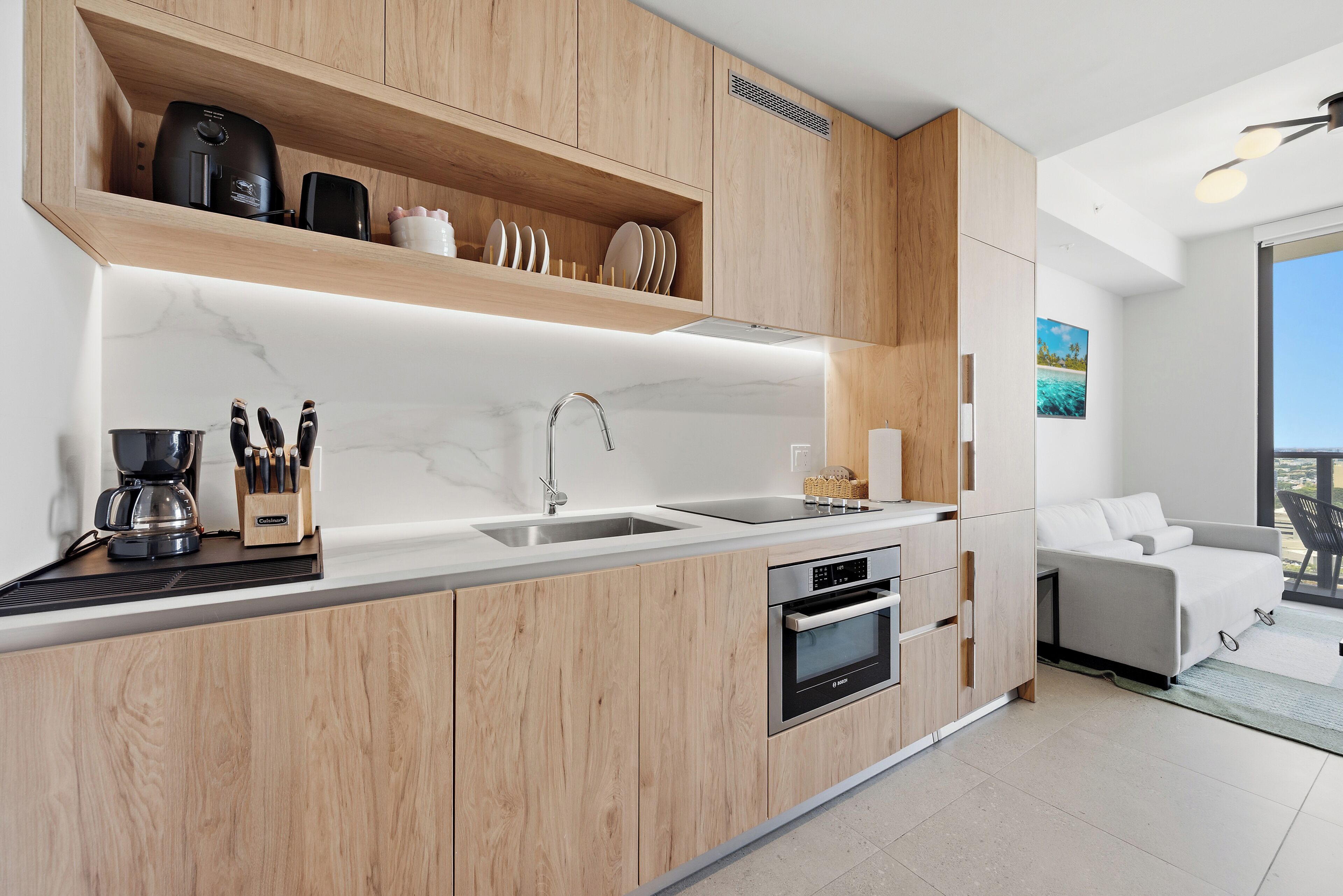 Une cuisine moderne avec des meubles en bois, un four encastré et une machine à café.
