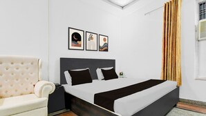 Ein Hotelzimmer mit einem Bett, einem Sessel und drei gerahmten Bildern an der Wand.