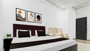 Ein Schlafzimmer mit einem großen Bett, einem Kopfteil, einem Sessel und drei gerahmten Kunstwerken an der Wand.