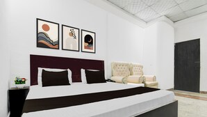 Ein Schlafzimmer mit einem großen Bett, einem Kopfteil, einem Sessel und drei gerahmten Kunstwerken an der Wand.