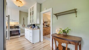 A kitchen with white cabinets, a wooden dining table with chairs, and a hanging light fixture.