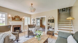 A spacious living room with a fireplace, a staircase, and a view of the outdoors.