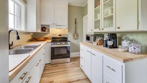 A compact kitchen with white cabinetry, a built-in oven, a coffee maker, and a window providing natural light.