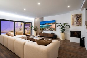 A modern living room with a large sectional sofa, a flat-screen TV, and a fireplace. - Luxury Villa with Private Pool Near Faro Beach, Offering Unparalleled Comfort! (Faro)
