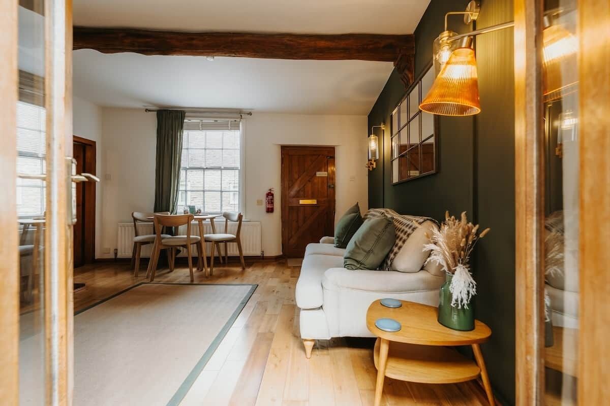 A cozy living room with a sofa, a small wooden side table, and a dining area with a table and chairs.