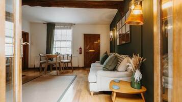 A cozy living room with a sofa, a small wooden side table, and a dining area with a table and chairs.