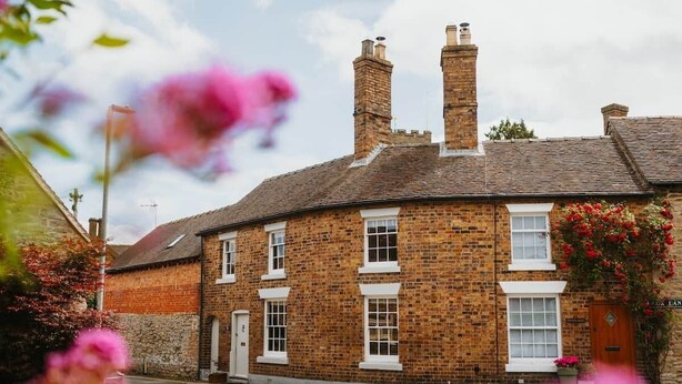 A traditional brick building with multiple windows and a chimney, likely a hotel or inn.