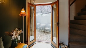 A room with a wooden door leading to an outdoor area with a table and chairs.