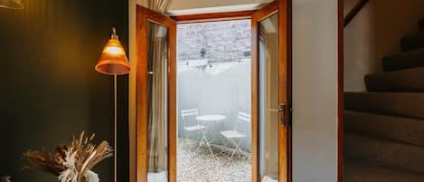 A room with a wooden door leading to an outdoor area with a table and chairs.