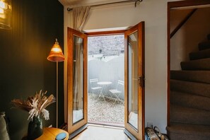 Ein Zimmer mit Holztür und Zugang zu einem Außenbereich mit Tisch und Stühlen.