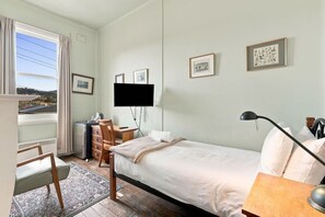 Ein Hotelzimmer mit Bett, Schreibtisch, Stuhl, Fernseher und gerahmten Bildern an der Wand.