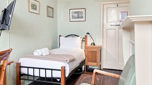 A bedroom with a bed, bedside table, lamp, and a television mounted on the wall. - Edinburgh Single Room (Hobart)
