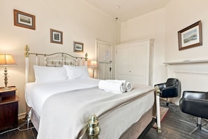 A hotel room with a bed, bedside lamps, a chair, and a door. - Edinburgh Family Room (Hobart)
