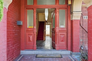 A red double door entrance with a staircase leading to an upper floor. - Edinburgh Family Room (Hobart)