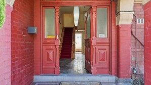 Ein roter Doppeltür-Eingang mit einer Treppe, die zu einer oberen Etage führt.
