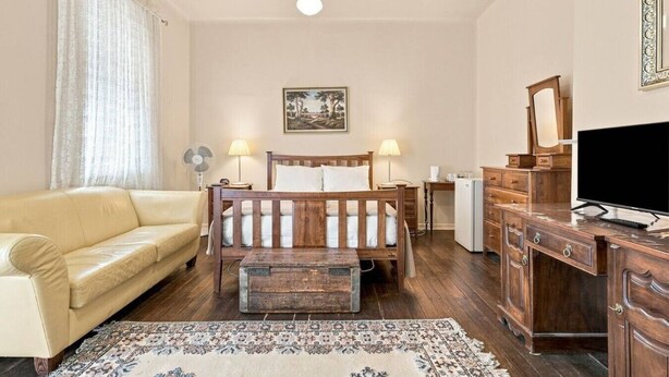 Ein Schlafzimmer mit einem hölzernen Bett, einem Sofa, einem Schreibtisch mit Fernseher und einer Kommode.