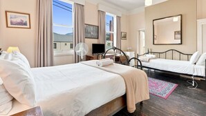 A hotel room with two beds, a TV, a fan, and a large window with curtains. - Edinburgh Queen & Single Rm + Ensuite (Hobart)