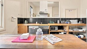 A modern kitchen with a wooden countertop, a built-in oven, a microwave, and a sink. - Edinburgh Queen & Single Rm + Ensuite (Hobart)