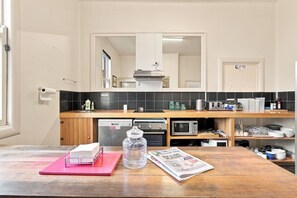 Uma cozinha moderna com bancada de madeira, forno embutido, micro-ondas e pia.