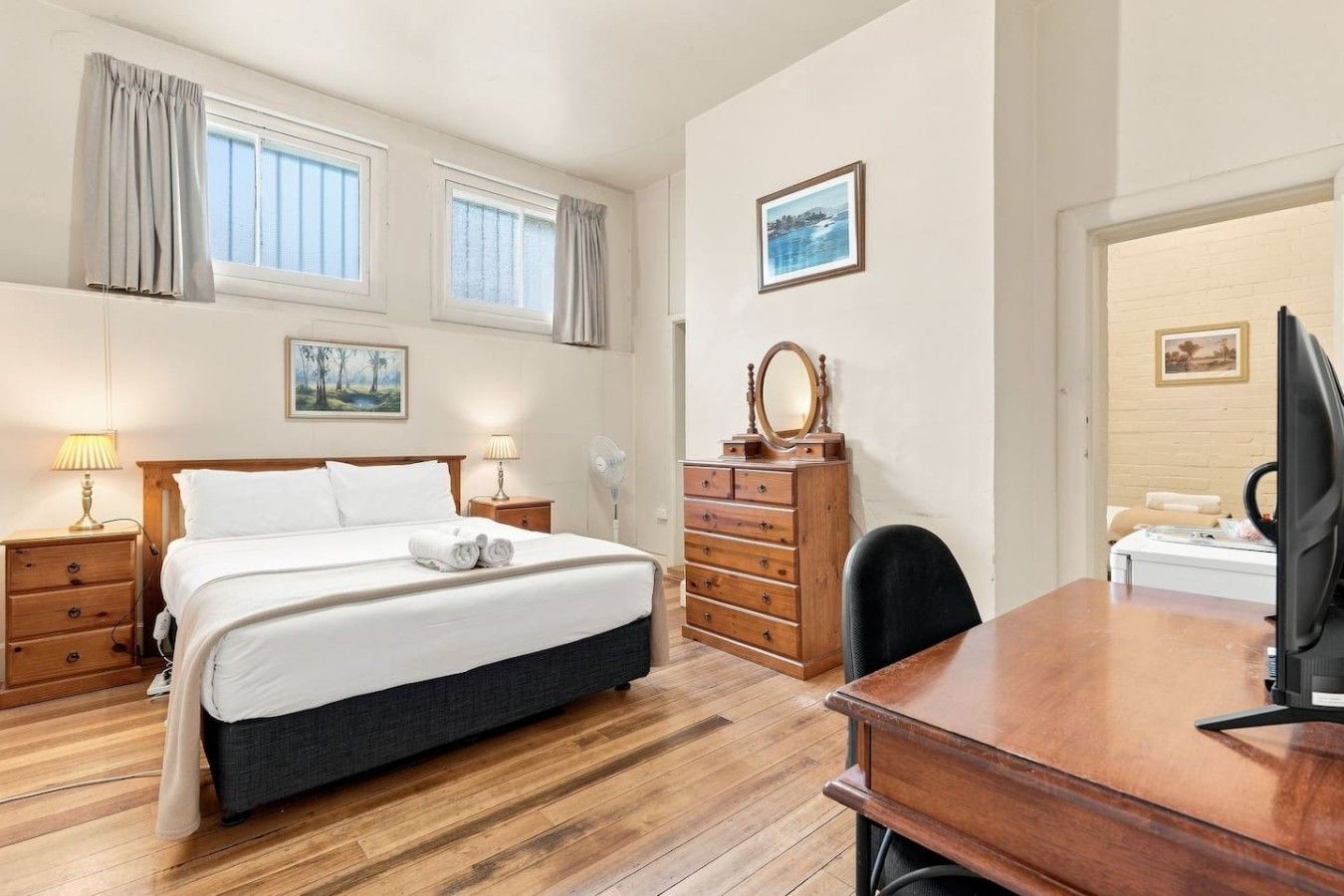 Een hotelkamer met een bed, nachtkastjes, een dressoir, een bureau, een stoel en een televisie.