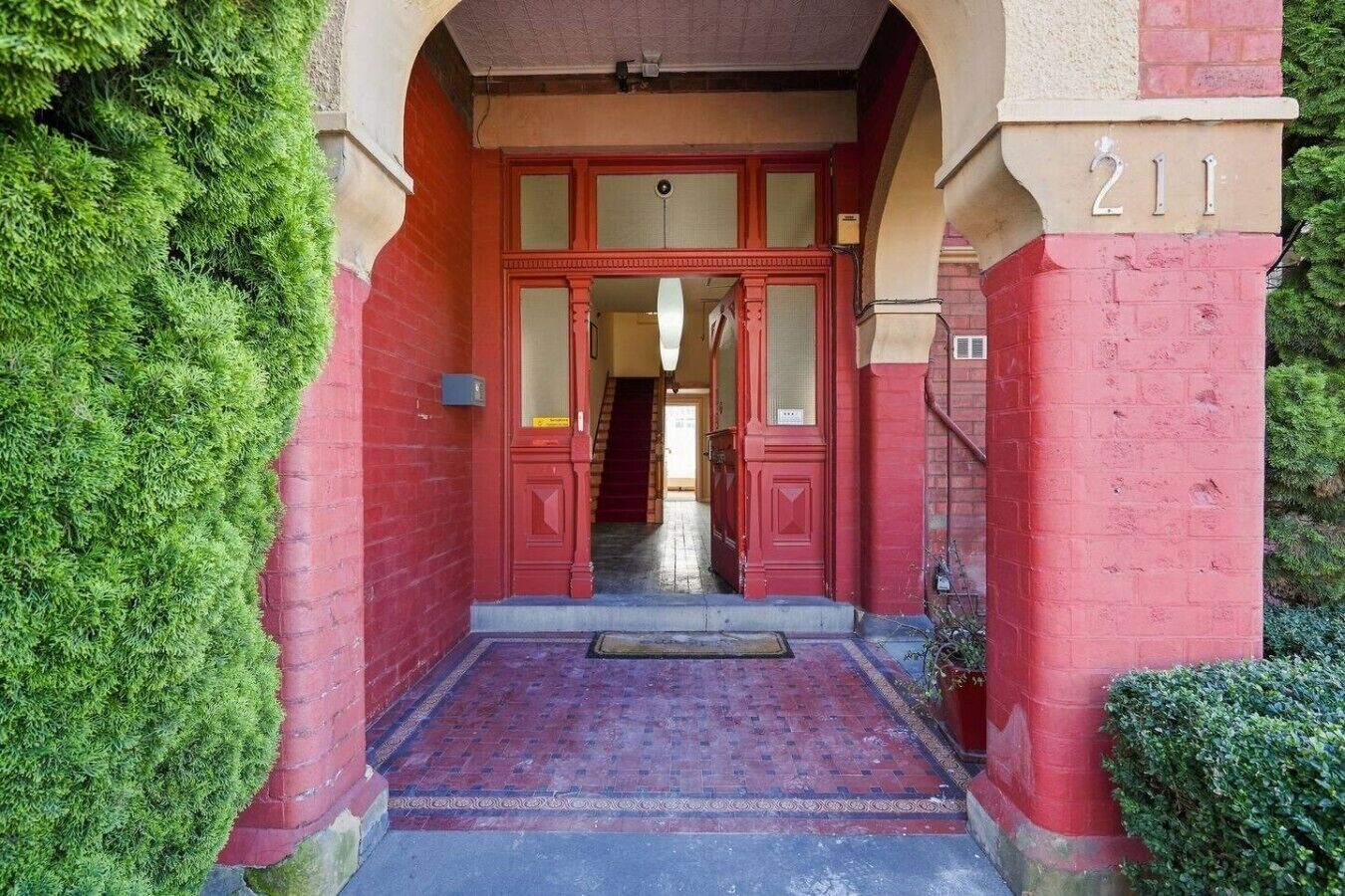 A red brick building entrance with a number '211' above the door.