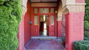 A red brick building entrance with a number '211' above the door. - Edinburgh Family + Ensuite | Hobart CBD (Hobart)