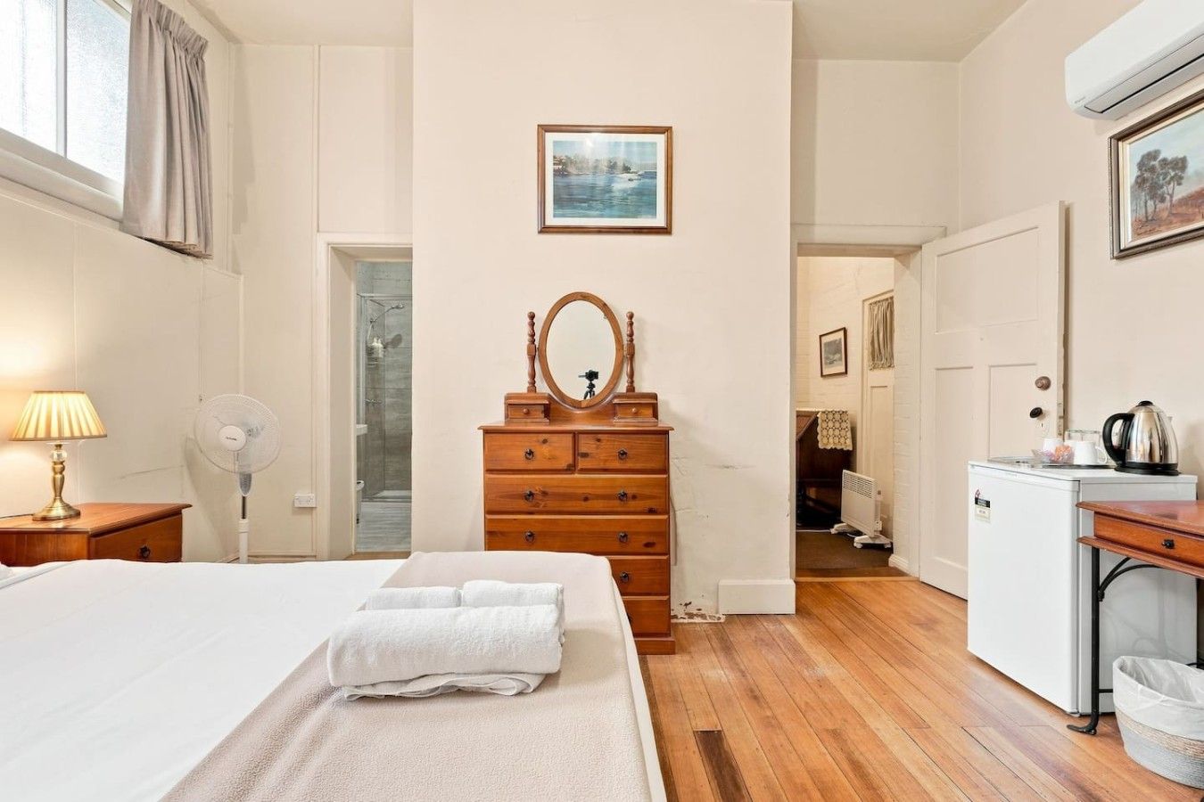Een hotelkamer met een bed, een dressoir, een spiegel en een kleine kitchenette.