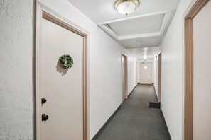 Un couloir aux murs blancs, doté d’un sol recouvert de moquette et de portes de part et d’autre.