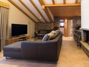 A living room with a large flat-screen TV, a sofa, and a stone fireplace. - Sonnhüsli Appartement/Fewo Appartement/Fewo by Interhome (Saas-Fee)
