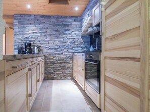 Eine schmale Küche mit Steinwand und Holzschränken.
