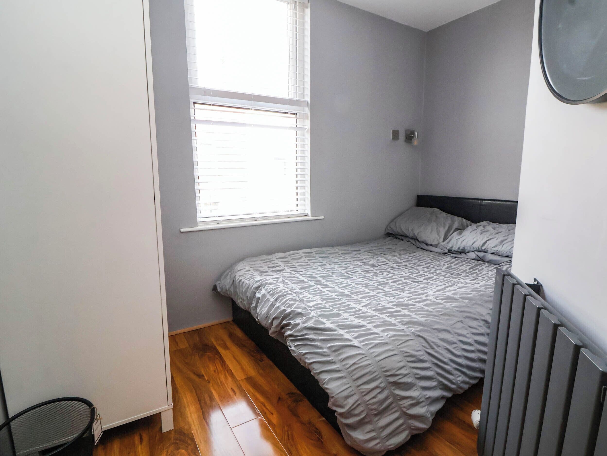 Un dormitorio con una cama individual, una ventana con persianas y un radiador.