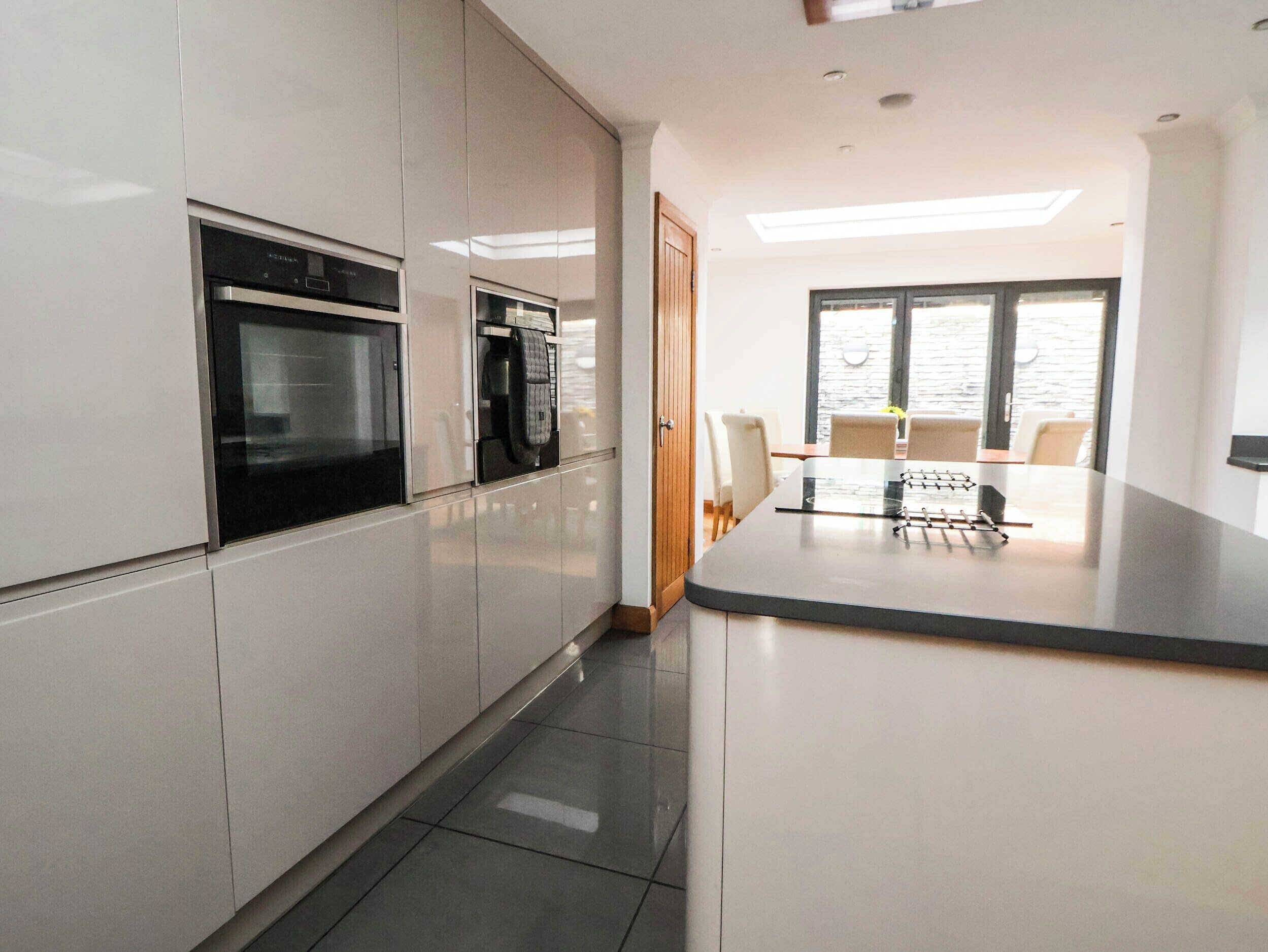 A modern kitchen with built-in appliances, a dining area with a table and chairs, and a large window providing natural light.