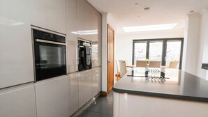 A modern kitchen with built-in appliances, a dining area with a table and chairs, and a large window providing natural light.