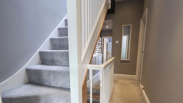 A carpeted staircase with white railings leading to a landing.