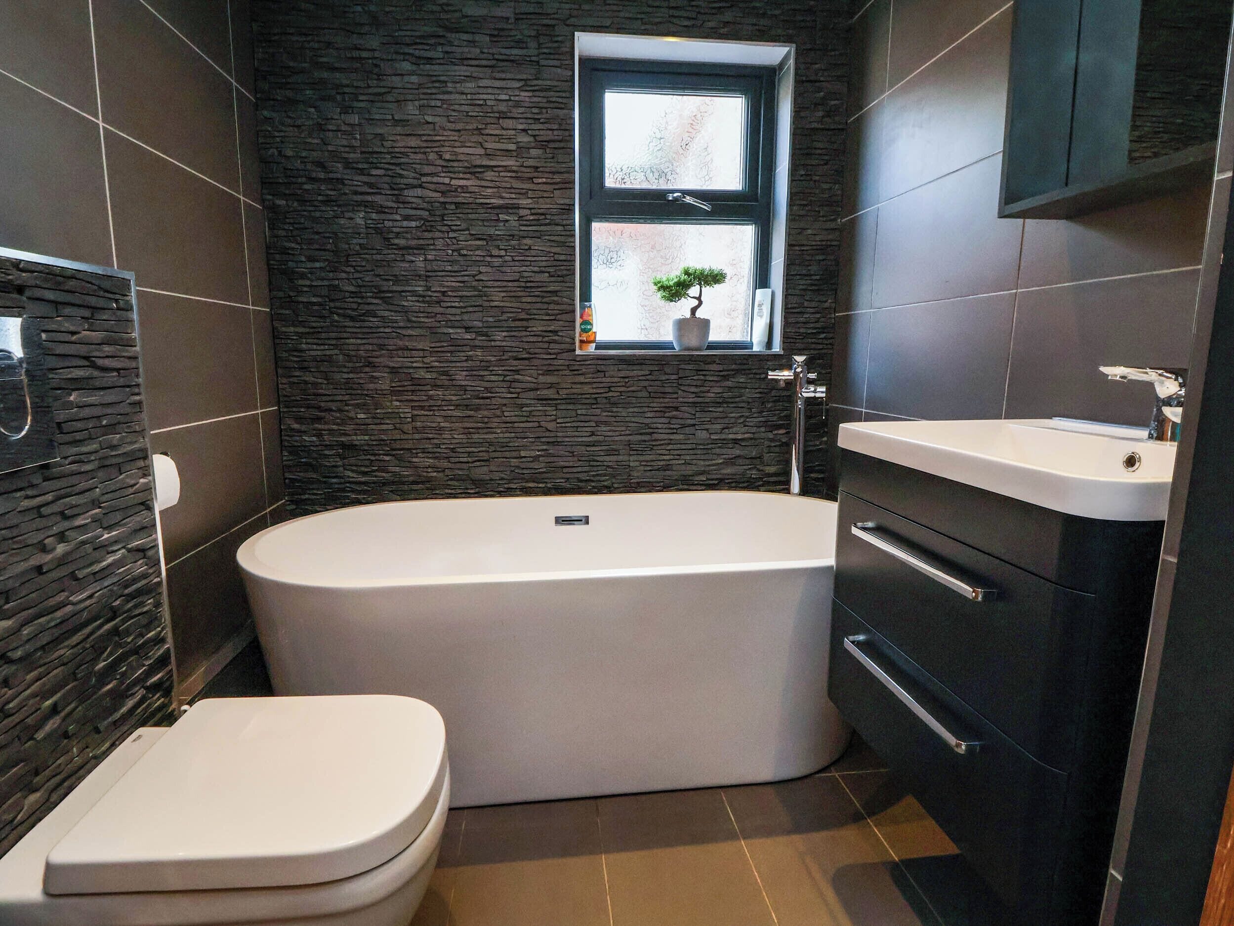 A modern bathroom with a freestanding bathtub, a toilet, and a sink.