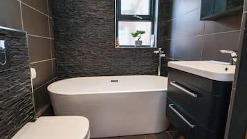 A modern bathroom with a freestanding bathtub, a toilet, and a sink.