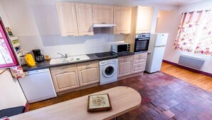 Une cuisine compacte équipée d’un lave-linge, d’un four à micro-ondes et d’un four traditionnel.