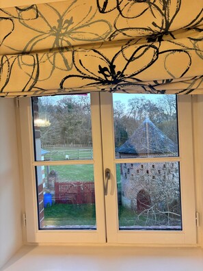 A window with a view of a brick structure and a fenced yard. - La Sellerie - Gîte de Charme à l'étage des écuries (Cour-Cheverny)