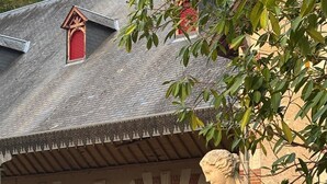 Une statue de pierre représentant une femme assise sur un piédestal, avec un bâtiment doté d’une porte rouge et une charrette en arrière-plan.